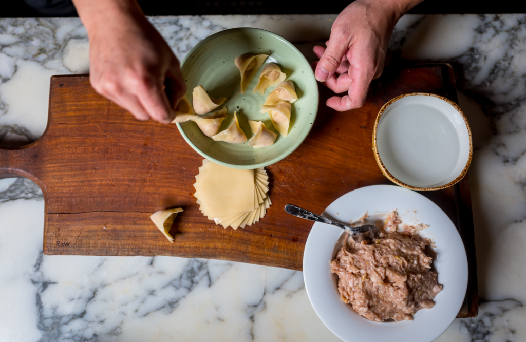 hands rolling fresh dumplings at Noodle Den