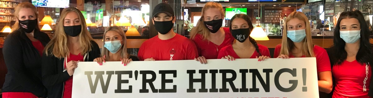 staff members with mask holding up a hiring sign