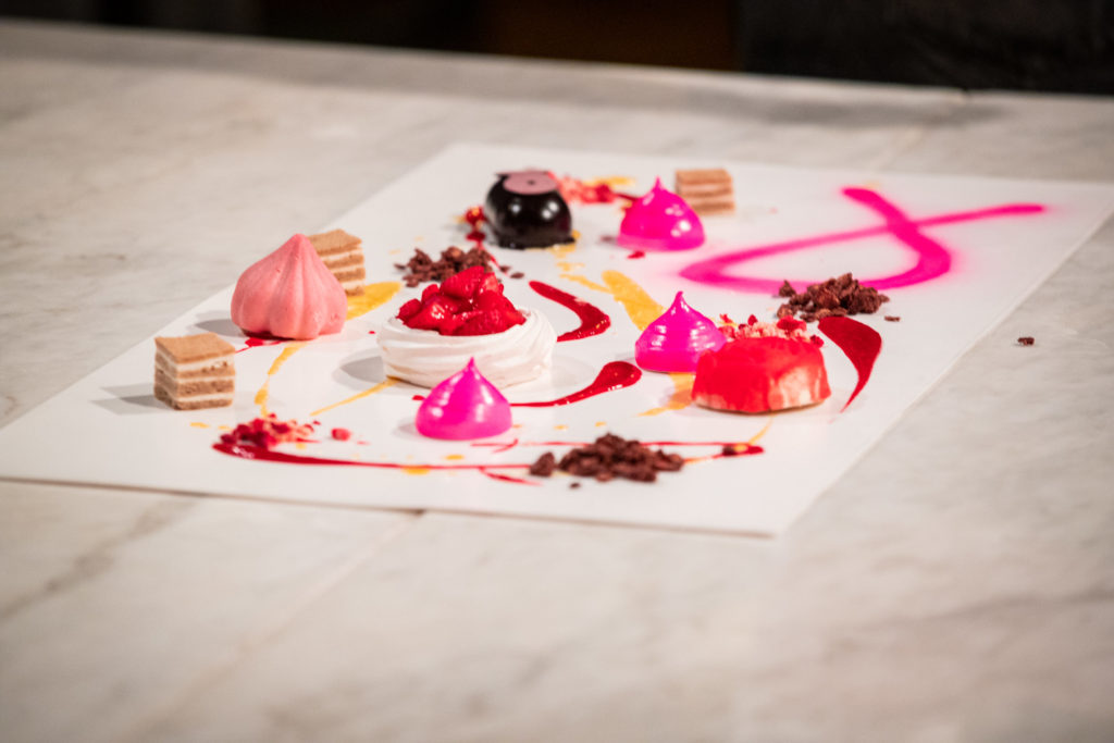 Dessert Graffiti - This picture shows a variety of hand crafted desserts on a blank canvas. All sitting on a table. Colors include pink, red, brown.
