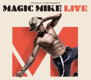 Male with top off and showing muscular abdomen is posing with the copy Magic Mike Live above him