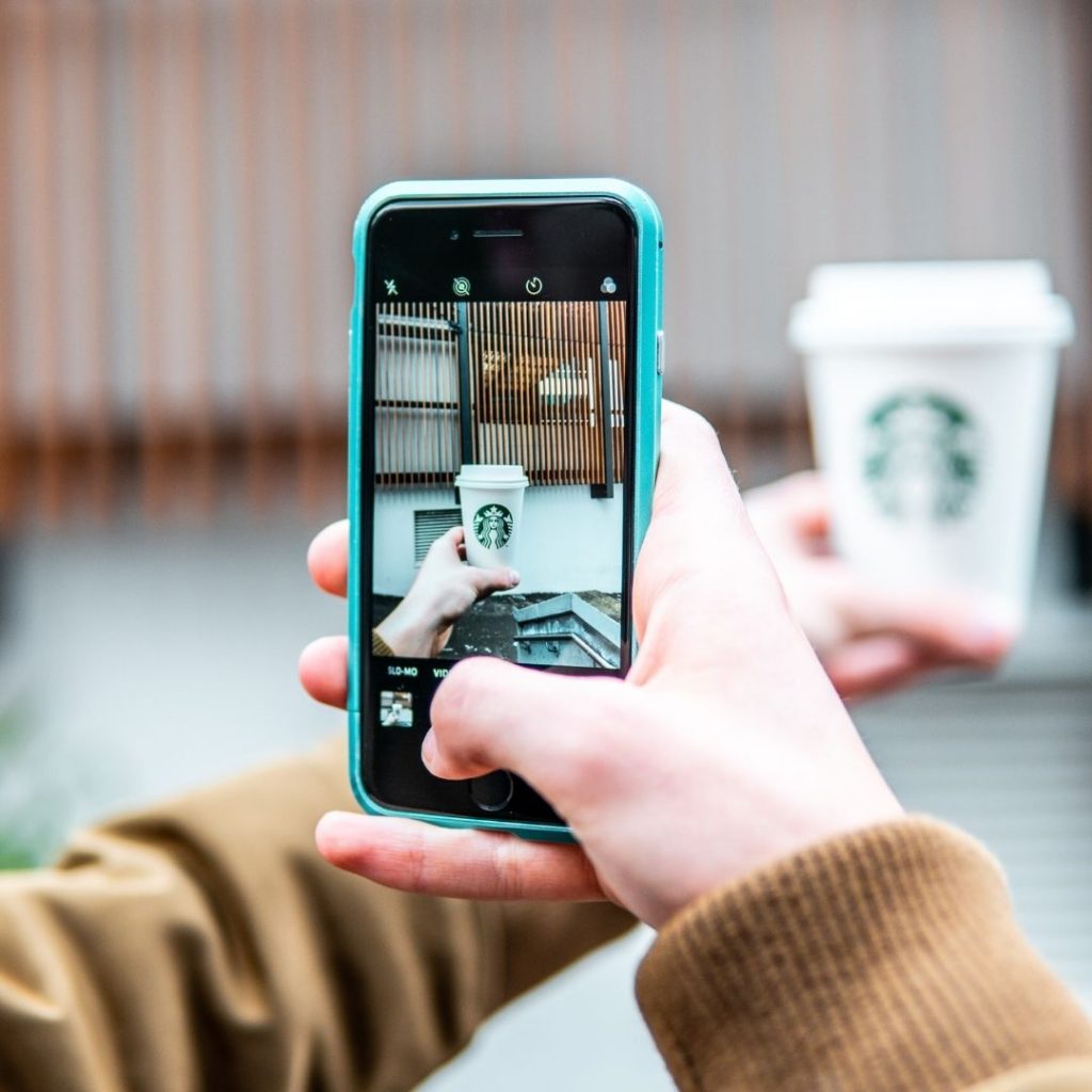 someone taking a picture of a Starbucks coffee cup with their phone