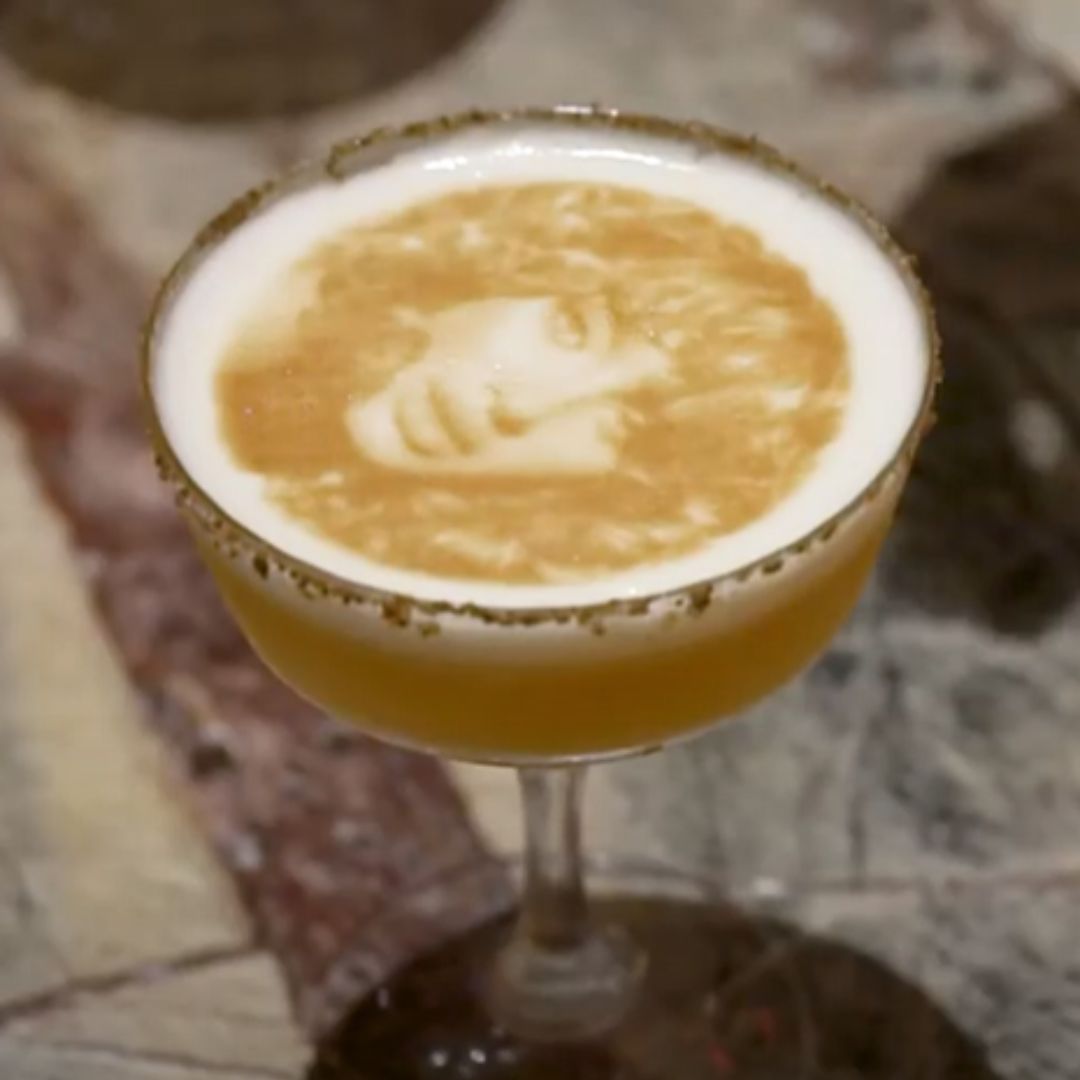 Two cocktails sitting on a table with text floating on the top of the drinks. One says Love Wins and shows a rainbow and the other says equality